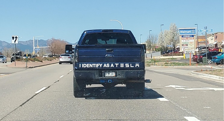 Pickup truck with sign: I Identify As A Tesla